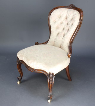 A Victorian walnut show frame nursing chair, upholstered in pink buttoned material, raised on cabriole supports  