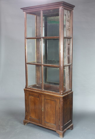 A Georgian mahogany display cabinet on cabinet, the upper section with moulded cornice, canted fluted columns to the side and mirrored back, fitted shelves enclosed by astragal glazed panelled doors, the base enclosed by panelled doors and raised on bracket feet 229cm h x 93cm w x 40cm d