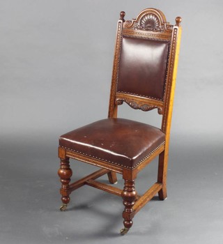 A Victorian carved light oak dining chair with arched cresting decorated a shell, the seat and back upholstered in brown rexine, raised on turned cup and cover supports with H framed stretcher 
