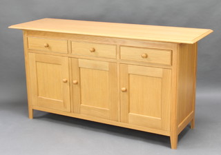 A Shaker style light oak sideboard fitted 3 drawers above triple cupboards, raised on tapered supports 82cm h x 161cm w x 51cm d 
