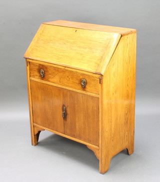 A 1930's oak bureau with fall front above 1 long drawer and cupboard 100cm h x 76cm w x 42cm d 