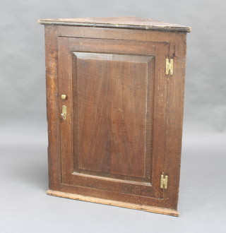 An 18th Century elm hanging corner cabinet with moulded cornice, fitted shelves enclosed by a panelled door with brass H framed hinges 94cm x 75cm x 38cm 