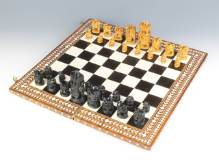 An Eastern carved hardwood chess set together with a hardwood and bone folding chessboard 
