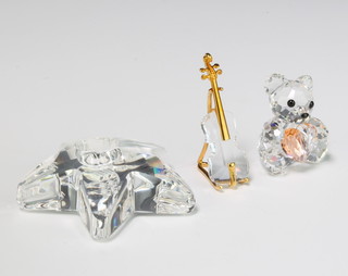 A Swarovski Crystal classics oboe and stand 5cm, a do. candle holder 6cm and a bear with heart 4cm 