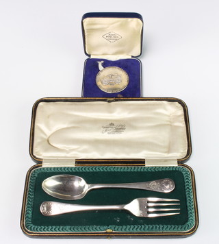 A cased silver fork and spoon Sheffield 1911 and a silver commemorative medallion 112 grams 