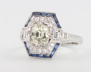 An 18ct white gold Art Deco style ring, the centre mine cut stone 1.05ct surrounded by brilliant cut diamonds and baguette cut sapphires, size N