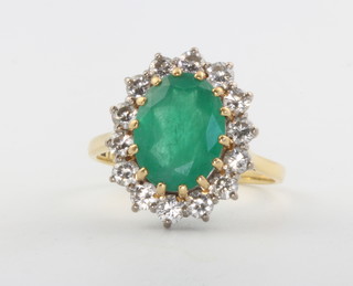 An 18ct yellow gold oval emerald and diamond cluster ring, the centre stone surrounded by 14 brilliant cut diamonds, size S 