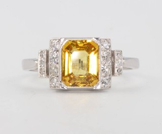 A yellow sapphire and diamond ring, the baguette cut centre stone approx. 1.8ct, flanked by 7 brilliant cut diamonds to each shoulder 0.25ct, size N 