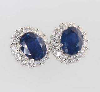 A pair of 18ct yellow gold oval sapphire and diamond cluster ear studs, the sapphires 4.57ct, the brilliant cut diamonds 1.18ct 