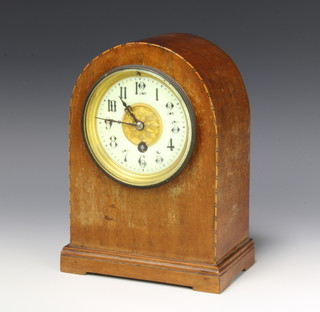 An Edwardian French timepiece with enamelled dial and Arabic numerals contained in an arch shaped inlaid mahogany case  