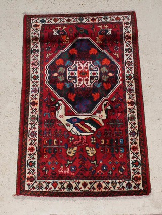 A Persian red and blue ground Qashqai rug with central medallion decorated a standing bird 155cm x 98cm 