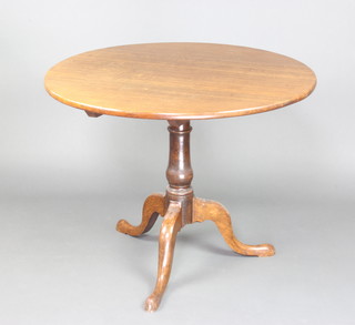 A circular Georgian oak tea table raised on a turned column and tripod supports 72cm x 90cm 