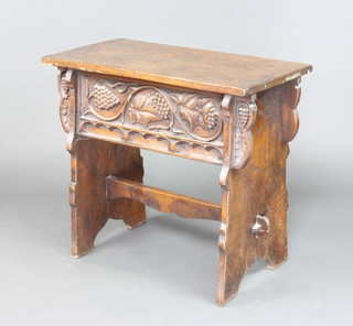 A rectangular carved oak centre table, the apron carved grapes raised on standard end supports with H framed stretcher 68cm x 76cm x 39cm 