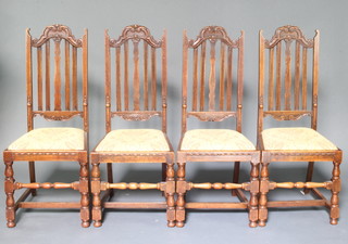 A set of 4 1920's Carolean style oak stick and rail back dining chairs with upholstered drop in seats, raised on turned and block supports