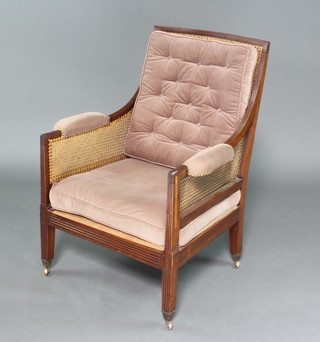A Georgian mahogany show frame library chair with cane seat and back, raised on square tapered supports ending in brass caps and casters 