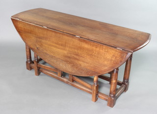 An oak oval drop flap hunt/wake table with double gateleg action raised on turned and block supports 73cm h x 165cm w  x 48cm when closed x 141cm when open 