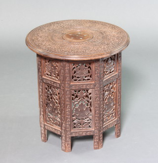 A circular carved hardwood inlaid brass occasional table raised on an octagonal pierced folding stand 47cm x 45cm 