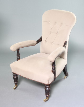A Victorian ebonised open arm chair, the seat and back upholstered in grey buttoned material, raised on turned supports