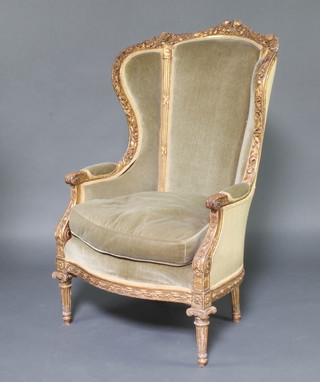 A 19th/20th Century French gilt plaster wing chair upholstered in green material, raised on turned and fluted supports 120cm h x 72cm w x 62cm d 