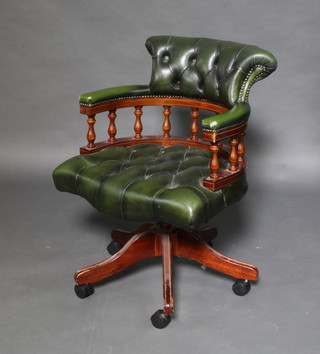 A Victorian style mahogany and leather revolving office chair upholstered in green buttoned back leather 