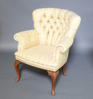 A Queen Anne style tub back chair upholstered in buttoned yellow floral material and raised on carved cabriole supports