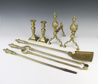 A pair of 19th Century brass candlesticks raised on square bases and with ejectors 18cm, a pair of Adam style fire dogs 28cm h x 30cm x 12cm and a 3 piece pierced brass fireside companion set with poker, shovel and tongs 