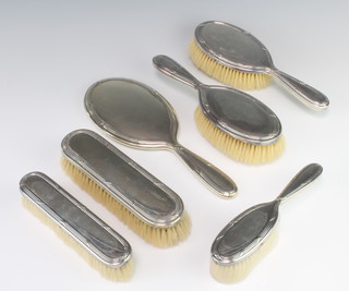 A French silver backed dressing table set comprising hand mirror, 2 hair brushes, 2 clothes brushes and a small brush 
