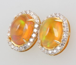 A pair of 18ct yellow gold fire opal cabochon cut ear studs, approx. 2.80ct each surrounded by brilliant cut diamonds 0.65ct 