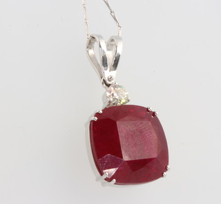 An 18ct white gold cushion cut ruby pendant 28.67ct surmounted by a brilliant cut diamond 0.60ct  (The ruby has been colour treated) 