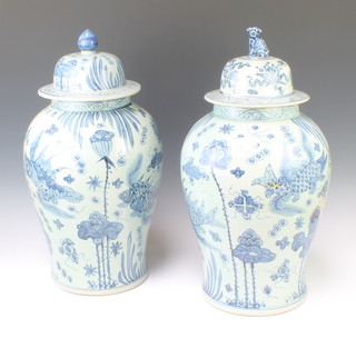 A pair of Chinese blue and white urns and covers, with different finials to the lids, 50cm h x 30cm diam.
