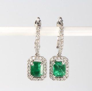 A pair of 18ct white gold emerald and diamond earrings, the emerald cut centre stones approx. 0.99ct surrounded by brilliant cut diamonds 0.28ct