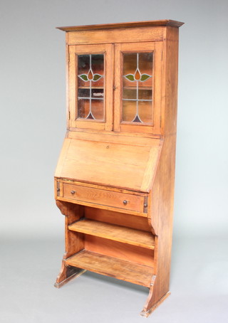 A Victorian Arts and Crafts oak bureau bookcase with moulded cornice, fitted shelves enclosed by lead glazed panelled doors, the fall front revealing a fitted interior above 1 long drawer with bookcase beneath 172cm h x 77cm w x 33cm d 
