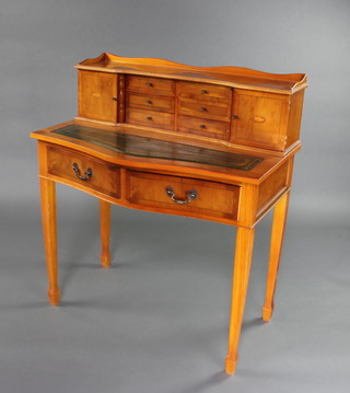 A Georgian stye yew writing table, the raised super structure to the back with 3/4 gallery fitted 6 short drawers flanked by a pair of cupboards with green inset writing surface above 2 long drawers, raised on square tapered supports with spade feet 102cm h x 91cm w x 55cm d 