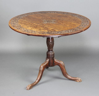 A 19th Century circular carved oak tea table, the top carved roses, raised on a turned column and tripod base with egg and claw feet 70cm x 90cm 