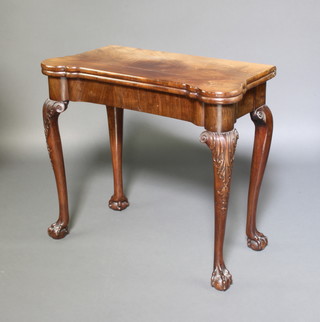 A 1930's Queen Anne style walnut card table with concertina action, having a plain surface with counter wells and candle wells, raised on cabriole ball and claw supports 74cm h x 84cm w x 42cm d 