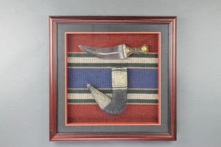 A Jambiya with 19cm blade contained in a white metal and leather scabbard, framed 