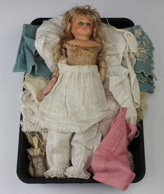 A 19th Century doll with composition head, leather body and biscuit porcelain arms and articulated legs (fingers and hand damaged) together with a collection of clothing 