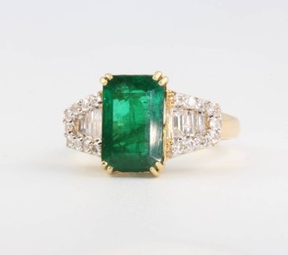 An 18ct yellow gold rectangular cut emerald and diamond ring, the centre stone 3.20ct flanked by baguette cut diamonds 0.24ct and brilliant cut diamonds 0.22ct, size M 