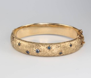 A 9ct yellow gold sapphire set engraved bangle, 21 grams 