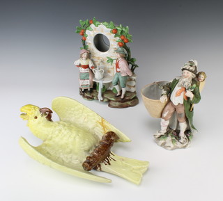 A Bretby wall pocket in the form for a parakeet 1226 35cm, a Continental bisque watch holder in the form of a couple at a fountain 25cm and a do. figure of a man with 4 children in his basket 21cm 