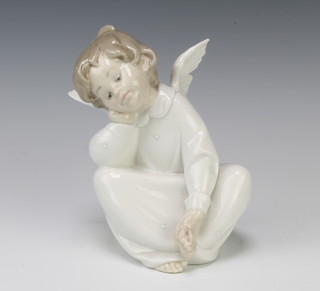 A Lladro figure of a seated angel holding his foot 15cm 