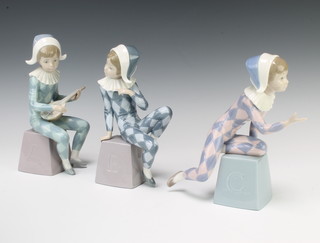 Three Lladro figures of child Pierrots sitting on lettered blocks 21cm 