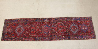 A blue, red and green ground Persian Heriz runner with 7 medallions to the centre within a multirow border 334cm x 85cm 