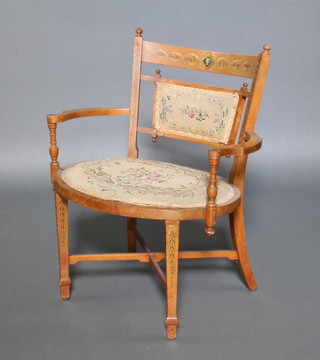 An Edwardian Sheraton Revival painted satinwood tub back open arm chair, the seat and back upholstered in Berlin woolwork, raised on square tapering supports with X framed stretcher 