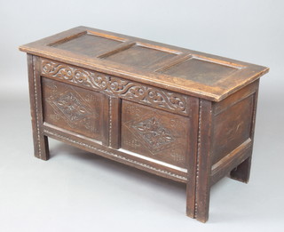 An 18th Century carved oak coffer of panelled construction the interior fitted a candle box 61cm h x 114cm w x 48cm d