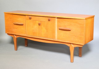 A 1960's teak sideboard fitted a drawer above a cocktail unit flanked by a pair of cupboards raised on shaped supports 76cm h x 127cm w x 40cm d 