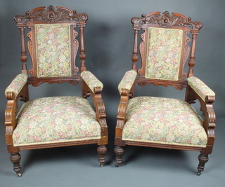 A pair of Victorian heavily carved walnut open arm chairs, the seats and backs upholstered in tapestry material, raised on turned and fluted supports 