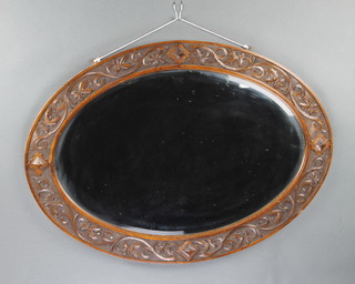 An oval bevelled plate wall mirror contained in a carved oak frame 64cm x 89cm 