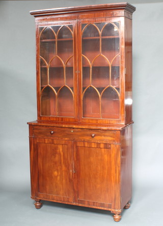 A Georgian mahogany bookcase on cabinet, the upper section with moulded cornice, fitted adjustable shelves enclosed by Gothic style astragal glazed panelled doors, the base fitted 1 long drawer above a cupboard enclosed by panelled doors, raised on bun supports 228cm h x 110cm w x 49cm d 