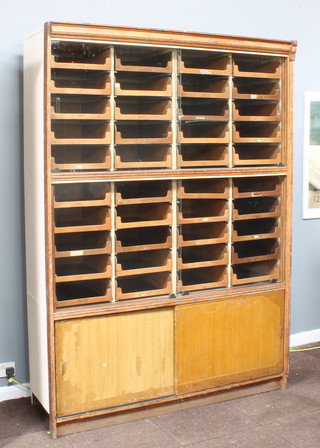 An early 20th Century oak and iron drapers cabinet, the upper section with moulded cornice fitted 2 compartments containing 40 shallow trays, the base fitted a shelf enclosed by a metal panelled door 217cm h x 153cm w x 57cm d